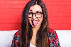 Girl in red plaid shirt sticking out her tongue to show what your tongue can tell you about your health